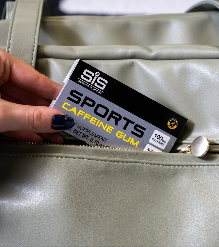 Eine Hand, die eine Packung SiS Sports Caffeine Gum aus einer Sporttasche nimmt