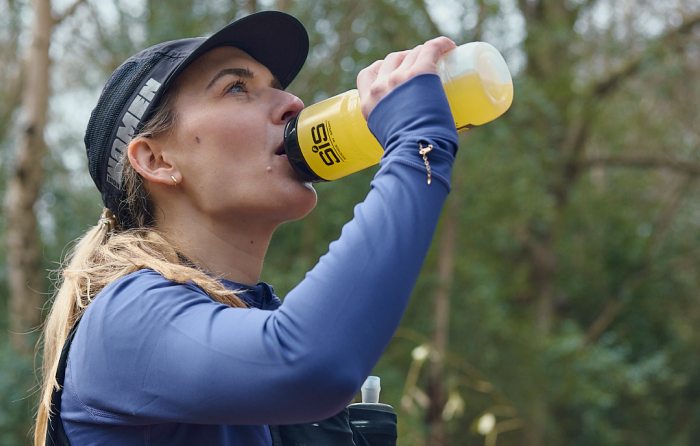 Un coureur professionnel fait une pause et s'hydrate avec une boisson SiS HYDRO dans une gourde SiS 