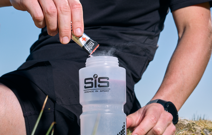 Athlete pouring a HYDRO+ sachet into a SiS Water Bottle