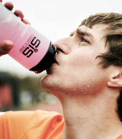Athlete drinking an electrolyte solution from a SiS water bottle