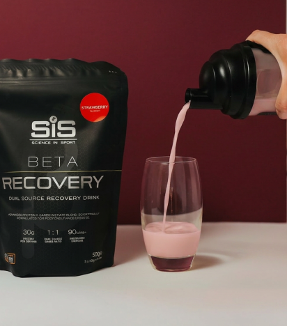BETA Recovery Shake being poured into a glass with a bag of BETA Recovery next to it
