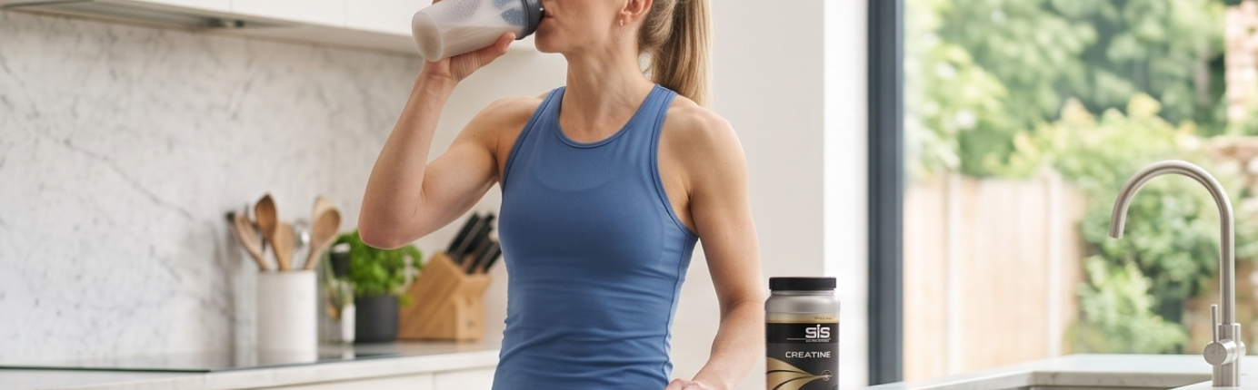 Athlete in blue top drinking a SiS Recovery drink mixed with creatine