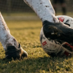 Footballer covered in mud kicking a ball