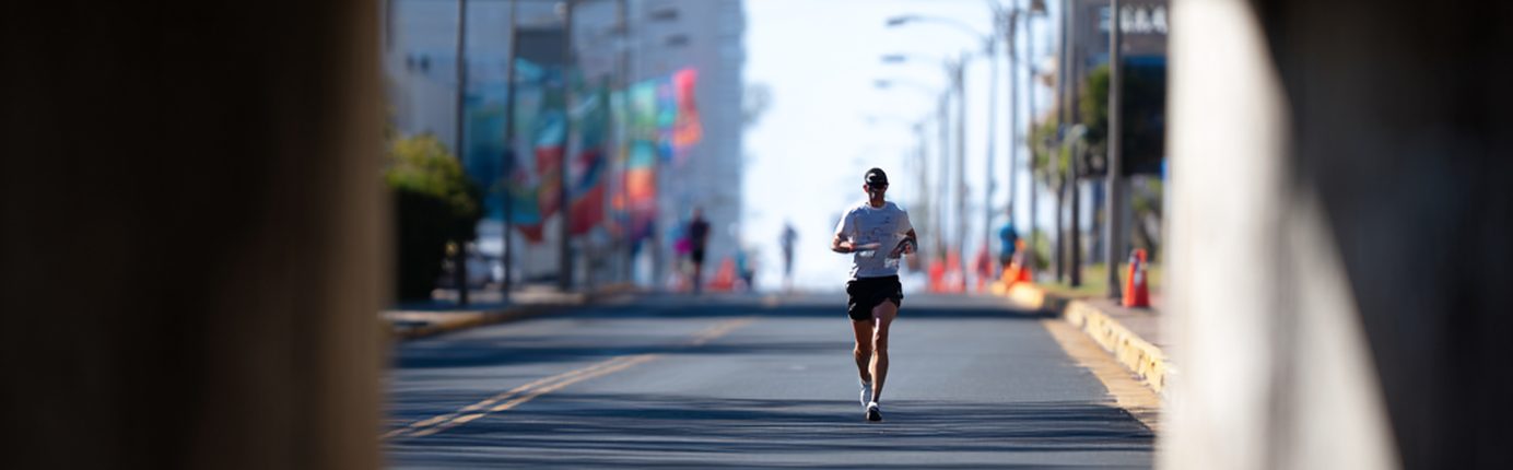 Runner framed through the opening of a dark underpass, city street beyond