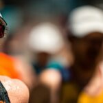 Close-up of a sweat-soaked runner in a cap and sunglasses pushing through a hot race