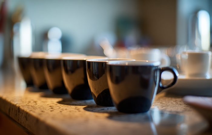 Une rangée de tasses à expresso vides alignées sur le plan de travail de la cuisine
