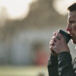 Un athlète en train de boire un café en plein air, concentré avant une séance d'entraînement
