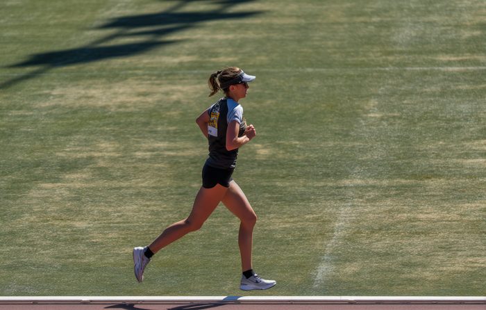 photo d'un coureur en pleine foulée sur une piste, sous un soleil radieux