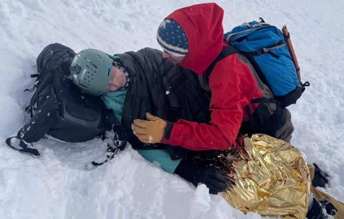 Ross Hewitt après l'avalanche, emmitouflé dans une couverture thermique, avec un ami qui veille sur lui